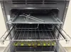 Interior view of an open oven with a baking tray and racks. Produktbild-Vorschau