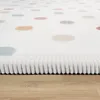 A close-up, angled view of a white rug with colorful polka dots, resting on a light wood floor. Produktbild-Vorschau