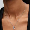 A close-up shot of a woman wearing a silver necklace with a small pendant. Produktbild-Vorschau