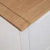 A close-up view of the corner of a wooden tabletop on a white cabinet. Produktbild-Vorschau