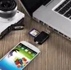 A collection of electronic devices including a camera, laptop, smartphone, and a USB card reader are arranged on a wooden surface. Produktbild-Vorschau