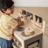 A young boy is playing with a wooden toy kitchen. Podgląd zdjęcia produktu