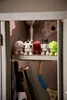 A collection of small, character-like figures are displayed inside a locker. Produktbild-Vorschau