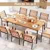 An outdoor dining set with a wooden table and chairs, set on a patio with a fireplace in the background. Produktbild-Vorschau