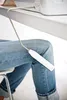 A person wearing jeans is sitting and holding a sewing machine accessory. Anteprima dell’immagine prodotto