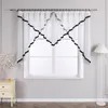A window with sheer white curtains trimmed with black ribbon, set in a room with a nightstand and a floor lamp. Produktbild-Vorschau