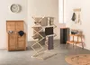 A laundry room scene with a wooden laundry hamper, a drying rack with towels, a black trash can, and a wooden stool with a basket of laundry. Náhľad obrázku produktu