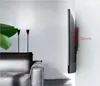 A TV mounted on a wall in a living room, next to a sofa and a large plant. Produktbild-Vorschau