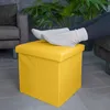 A person's feet in socks resting on a yellow ottoman in a living room setting. Produktbild-Vorschau