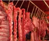 A close-up view of raw meat cuts hanging from hooks on a metal rack. Produktbild-Vorschau
