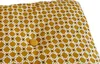 A close-up view of a yellow cushion with a white geometric pattern and a single button. Náhled obrázku produktu