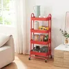 A red kitchen cart with items on its shelves, placed next to a sofa and a cabinet. Produktbild-Vorschau
