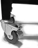 A close-up of a caster wheel with a brake on a black metal frame. Produktbild-Vorschau