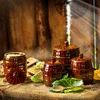 A rustic still life featuring ceramic fermentation pots, cabbage, and a wooden spoon, set against a wooden background. Podgląd zdjęcia produktu