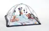 A baby is lying on a playmat under a gymini arch with toys hanging. Náhled obrázku produktu
