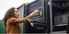 A woman is working on a server rack, inserting a drive. Produktbild-Vorschau