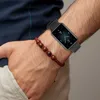 A close-up shot of a person's arm wearing a smartwatch and a beaded bracelet. Náhled obrázku produktu
