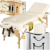 A cream-colored massage table with wooden legs and accessories, presented in a studio setting. Náhled obrázku produktu