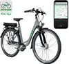 A studio shot of a gray and green electric bicycle with a smartphone displaying a map and app interface next to it. Produktbild-Vorschau