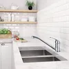A modern kitchen sink area with a chrome faucet, double sink, and white subway tile backsplash. Produktbild-Vorschau