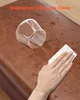A hand is wiping water off a brown leather ottoman with a white cloth, demonstrating its waterproof and easy-to-clean feature. A glass is also on the ottoman with water spilled around it. Náhľad obrázku produktu