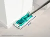 A mop head with a measuring tape indicating its size is shown cleaning a corner of a room. Produktbild-Vorschau