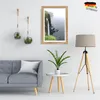 A living room scene with a sofa, a framed picture of a waterfall, hanging plants, and a floor lamp. Produktbild-Vorschau