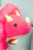 Close-up of a pink plush dinosaur toy with yellow accents. Voir les images du produit