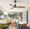 A modern ceiling fan with wooden blades is installed on a white patio ceiling, overlooking a scenic outdoor living area with furniture and lush greenery. Anteprima dell’immagine prodotto
