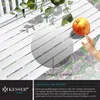A close-up of a white wooden garden bench with an apple and a child's hand reaching for it, with greenery and stone paving in the background. Water droplets are visible on the bench. Produktbild-Vorschau