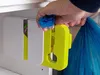 A hand is shown using a plastic bag sealer to seal a blue plastic bag. Náhled obrázku produktu
