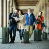 Four people are walking in a covered walkway with luggage. Anteprima dell’immagine prodotto