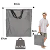 A man is holding a folded gray bag, with dimensions and weight indicated. Another larger gray bag is shown in the background. Produktbild-Vorschau