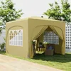 A khaki-colored pop-up gazebo is set up on a grassy lawn, with a wooden deck in the foreground. The gazebo has windows and an open entrance revealing chairs and a small table inside. Podgląd zdjęcia produktu