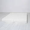 A white, two-part folding mat is shown lying flat on a light-colored wooden floor against a white wall. Anteprima dell’immagine prodotto
