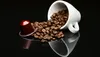 A white coffee cup is tipped over, spilling coffee beans onto a reflective black surface. A single red coffee capsule is placed to the left of the spilled beans. Produktbild-Vorschau