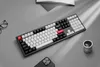 A keyboard is placed on a gray surface next to a pair of glasses, a book, and a smartphone. Produktbild-Vorschau