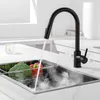 A black kitchen faucet is shown in use, with water running into a sink containing a basket of vegetables. Produktbild-Vorschau