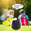 Two children wearing backpacks are sitting on grass, with a close-up of a walkie-talkie in the foreground. Produktbild-Vorschau