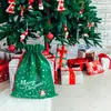 A green Christmas gift bag with white snowflakes and a Christmas tree design, placed under a decorated Christmas tree surrounded by wrapped gifts. Produktbild-Vorschau