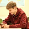 A young person wearing headphones and looking at a phone. Anteprima dell’immagine prodotto
