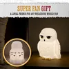 A white owl-shaped lamp is displayed on a wooden surface next to a dark background. A smaller inset image shows the lamp with a frosted effect and black bird silhouettes. Anteprima dell’immagine prodotto