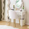 A white plush chair with gold legs sits in front of a white vanity table with a lighted mirror and various cosmetic products. Podgląd zdjęcia produktu