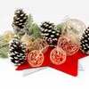 Christmas decorations including pine cones, pine branches, and string lights in the shape of spheres. Náhľad obrázku produktu