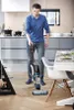 A man is cleaning the floor in a modern kitchen with a cordless vacuum cleaner. Produktbild-Vorschau