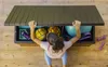 A person is opening a storage box filled with exercise equipment. Produktbild-Vorschau