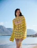 A woman stands on a beach in front of the ocean and mountains. Produktbild-Vorschau