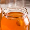 Close-up of the top of a glass jar filled with an orange liquid. Podgląd zdjęcia produktu