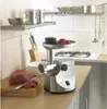 A kitchen counter with a meat grinder, raw meat, and kitchen utensils. Podgląd zdjęcia produktu