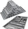 A stack of silver-grey drawer organizers and a close-up of one organizer filled with kitchen utensils. Produktbild-Vorschau
